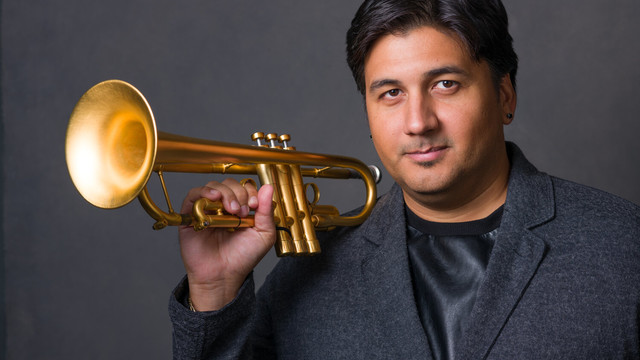 Professional headshot of Michael Rodriguez, holding his trumpet